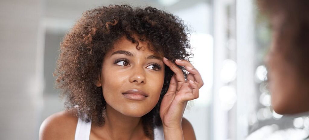 woman looking in the mirror after her eyelid surgery in New Jersey